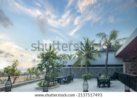 Wooden table chairs bench on an outside restaurant with green plants and trees with blue sky background