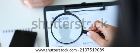 Employer looking at application form with magnifying glass closeup