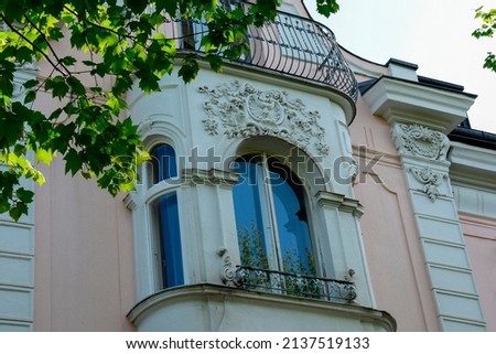 The facade of the building with a balcony over a large window with an ornament. Salzburg. Austria. May 2019