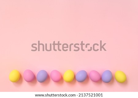 Top view layout of colorful painted Easter eggs on pink background. Greeting card, poster, banner for Happy Easter. Copy space for your text.