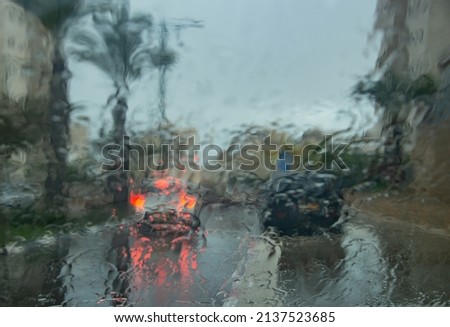 Blurred image of traffic through the windshield of a car during heavy rain on an autumn day
