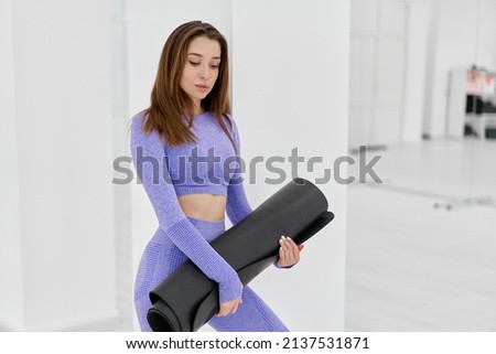 Woman in trendy colour sportswear holding sports mat
