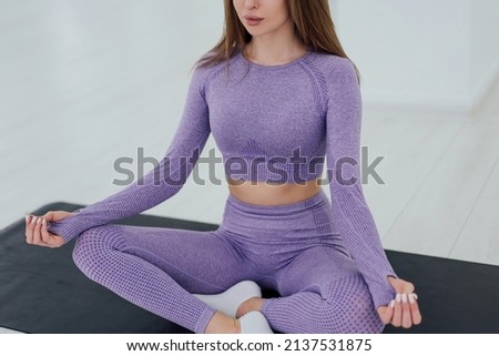 Woman in trendy colour sportswear sitting in position lotus, yoga, relaxing