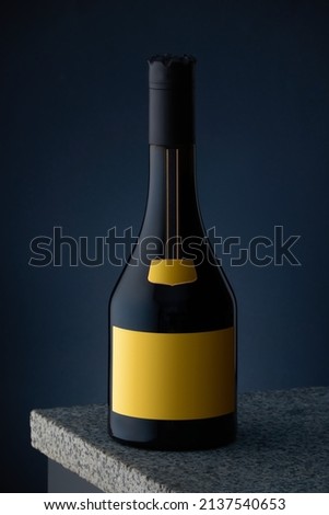 A bottle of expensive alcohol, whiskey, cognac, brandy with a yellow label on a marble surface and a dark blue background.