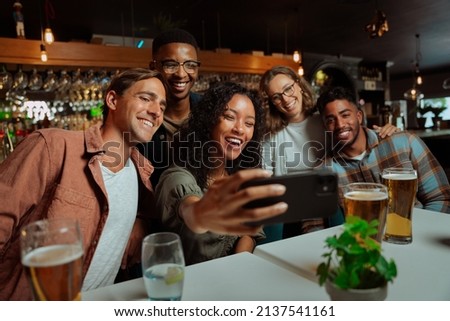 Group of young adult friends eating dinner at restaurant taking selfies