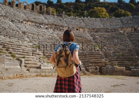 walk in Antalya Turkey on warm October afternoon. Pretty tourist woman with backpack at ruins of ancient city of Perge Royalty-Free Stock Photo #2137548325