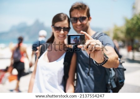 Heres something to remember me by. Shot of a young couple taking a self-portrait at the beach.