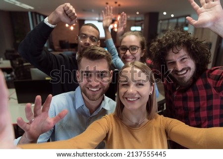 Group of business people during break from the work taking selfie picture while enjoying free time in relaxation area at modern open plan startup office. Selective focus 