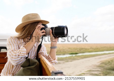 Beautiful female tourist with photo camera on safari Royalty-Free Stock Photo #2137559901