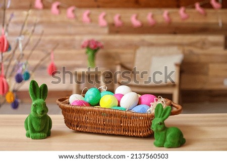 Basket with Easter eggs and rabbits on table