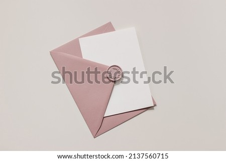 Blank wedding greeting card, invitation mockup scene in sunlight. Closeup of pink envelope with decorative wax seal on table. Birthday stationery template. Flat lay, top view. Feminine composition. Royalty-Free Stock Photo #2137560715
