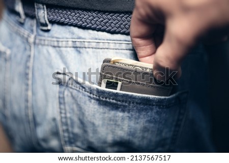 Pickpocket stealing wallet with money and credit card from back pocket of jeans Royalty-Free Stock Photo #2137567517