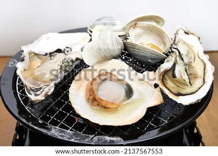 Seafood barbecue grilling shellfish on the net Royalty-Free Stock Photo #2137567553