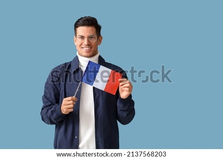 Handsome young man with flag of France on blue background