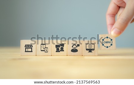 Omnichannel marketing concept. Digital online marketing commerce sale. Customer engagement integrated online and offline channels. Hand holds flat wooden cube with omni text standing with omni icons. Royalty-Free Stock Photo #2137569563