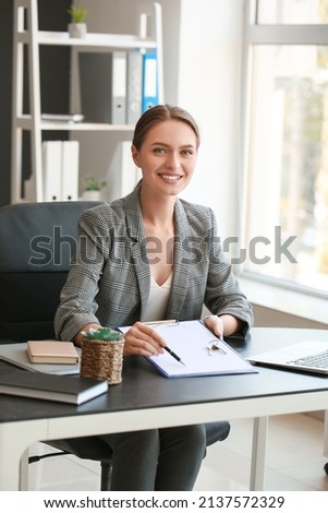 Real estate agent with clipboard and key from house in office