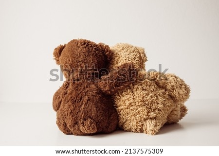 Rear view of two sitting teddy bears in hug. Friendship, togetherness, white background.  Royalty-Free Stock Photo #2137575309