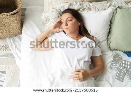 Sick woman laying in the bed covering her face with hand, cold, flue and coronavirus disease concept Royalty-Free Stock Photo #2137580515
