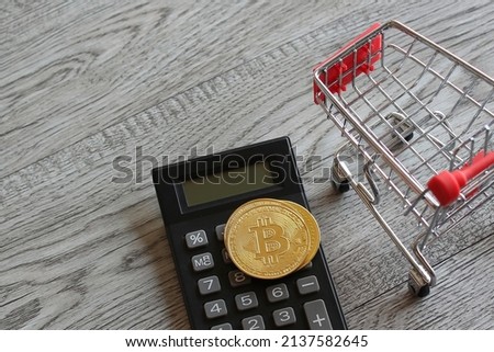 Bitcoin, calculator and shopping trolley. Cryptocurrency and business concept.