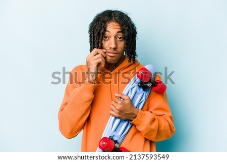 Young African American skater man isolated on blue background with fingers on lips keeping a secret.