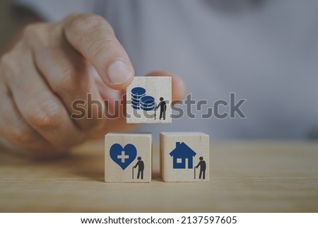 senior's hand holding coin with  elderly icon on wooden cube block above the others for health insurance ,pension , retirement ,elderly care, nursing home concept