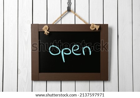 Small chalk board with word Open on white wooden wall