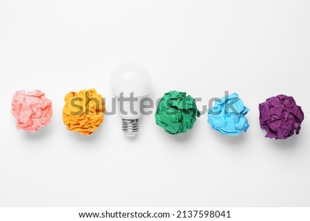 Creative flat lay composition with lightbulb and colorful paper balls on white background. Idea concept