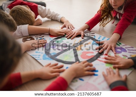 Schoolchildren making poster of peace sign at school.