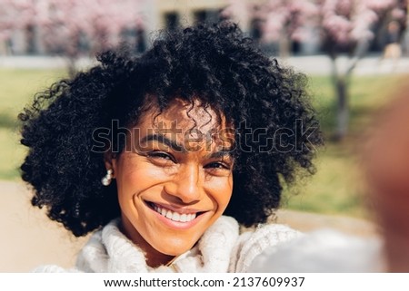 Attractive black woman taking a selfie photo on the street Beautiful smiling Hispanic girl, walking around the city in spring outdoors. Beauty lifestyle concept