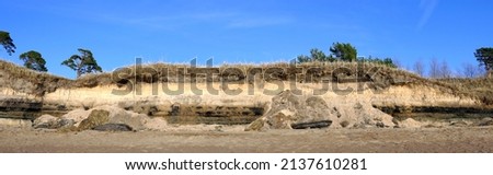 Washed sea coast after a storm. Geological section of the seashore. Panoramic photography.
