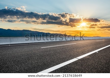 Asphalt road and mountains with beautiful clouds at sunrise