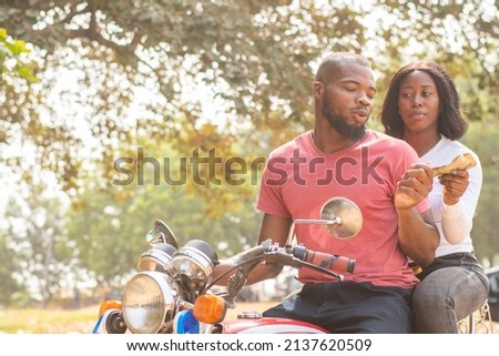 african lady on a bike gives the rider money Royalty-Free Stock Photo #2137620509