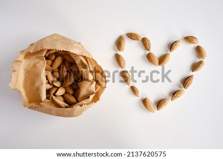 Almonds in a craft paper bag and a heart of nuts on a light background. Healthy food. Healthy vegetarian natural snack. organic food. Nuts close-up
