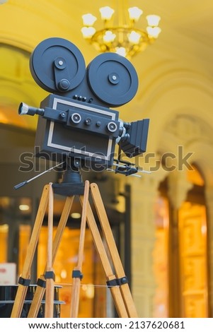 Vintage movie camera on a tripod , model, on abstract gold background. Cinema concept and antiquities