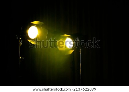 Bright yellow spotlights on dark stage, space for text
