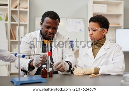 Portrait of African American teacher demonstrating science experiments in school chemistry lab Royalty-Free Stock Photo #2137624679