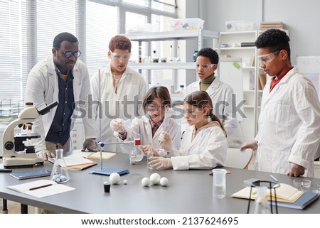 Large group of diverse children wearing lab coats in chemistry class while enjoying science experiments Royalty-Free Stock Photo #2137624695