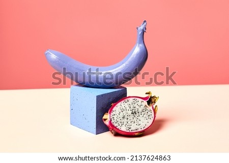 Minimal shot of single purple banana set on podium against pink background with tropical dragon fruit, girly lifestyle and dieting concept, copy space