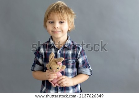 Little toddler child, blond boy, playing with handmade little stuffed knitted toy