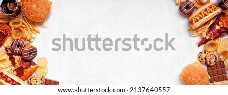 Junk food double border over a white marble banner background. Assortment of take out and fast foods. Pizza, hamburgers, french fries, chips, hot dogs, sweets. Overhead view with copy space. Royalty-Free Stock Photo #2137640557