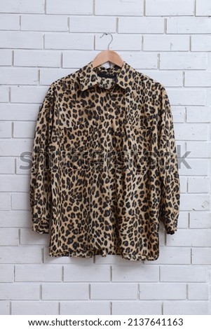 female fashion leopard print seamless pattern ,shirt on hanger  on wall background