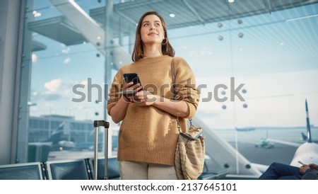 Airport Terminal: Happy Traveling Caucasian Woman Waiting at Flight Gates for Plane Boarding, Uses Mobile Smartphone, Checking Trip Destination on Internet. Smiling White Female in Airline Hub Royalty-Free Stock Photo #2137645101