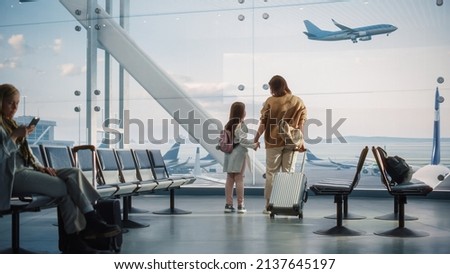 Airport Terminal: Beautiful Mother and Cute Little Daughter Wait for their Vacation Flight, Looking out of Window for Arriving and Departing Airplanes. Young Family in Boarding Lounge of Airline Hub Royalty-Free Stock Photo #2137645197