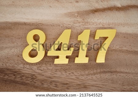 Wooden  numerals 8417 painted in gold on a dark brown and white patterned plank background.