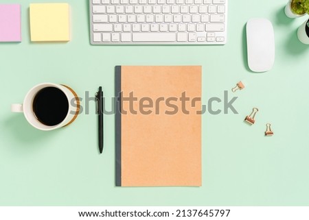 Creative flat lay photo of workspace desk. Top view office desk with keyboard, mouse and mockup black notebook on pastel green color background. Top view mock up with copy space photography.