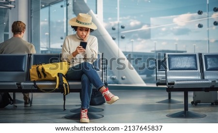Airport Terminal: Black Woman Waits for Flight, Uses Smartphone, Receives Shockingly Bad News, Misses Flight. Upset, Sad, and Dissappointed Person Sitting in a Boarding Lounge of Airline Hub. Royalty-Free Stock Photo #2137645837
