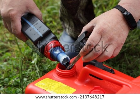 Fuel mix preparation with petroleum and special 2 T oil for a two stroke outboard motor in a red boat fuel tank before use Royalty-Free Stock Photo #2137648217