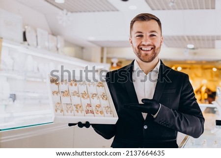Sales man at jewelry shop demonstrating jewellery Royalty-Free Stock Photo #2137664635