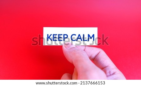 Marketing and Communications Concept. Keep Calm text words typography, business motivational inspirational concept. Red background. Man's hand holding a white paper that says Keep Calm. 