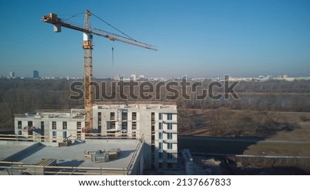 Tower crane on bright blue sky copy space background, city landscape stretching to horizon. Drone aerial photography.
